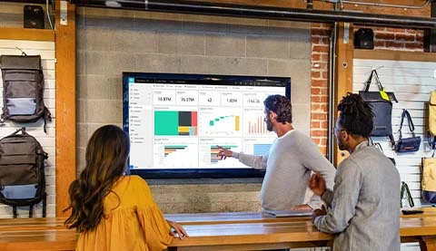 Ein Mann erkl&auml;rt einer Frau und einem weiteren Mann etwas anhand Diagrammen. 