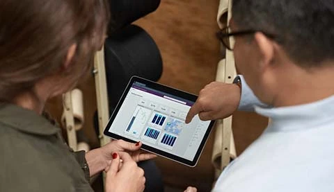 Zwei Menschen blicken auf verschiedene Diagramme auf einem Tablet PC.