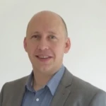 A man wearing a suit and tie smiling at the camera