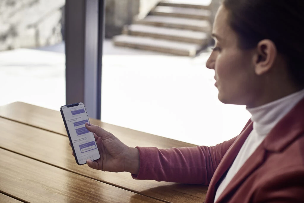 Woman at table using Microsoft Teams chat on an iPhone