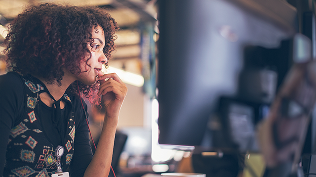 woman deep in thought looking at the monitor.