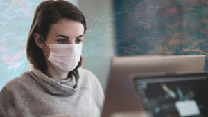 woman with a face mask working on her laptop