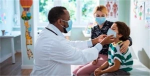 Doctor checking on a child patient sitting next to his mom