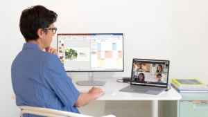 Woman working on a desk, looking at the video chat on her laptop