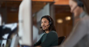 A man wearing a headset and looking at a computer screen