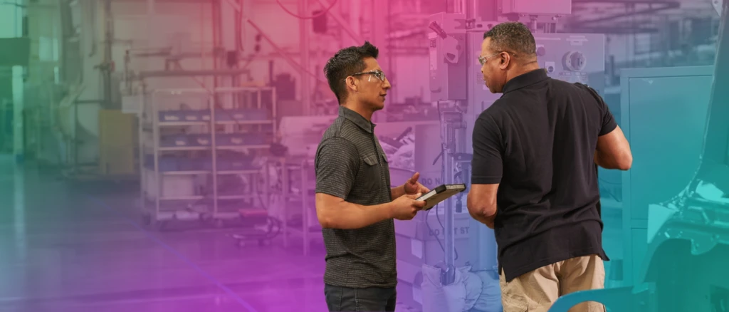 A man holding a tablet and talking to another man