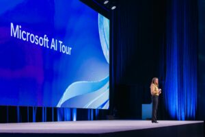 Tracy Galloway, Microsoft executive, speaking onstage at Microsoft AI Tour with a blue “Microsoft AI Tour” backdrop.