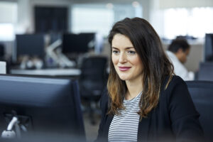 Smiling business woman using a computer, sitting at a desk in an office