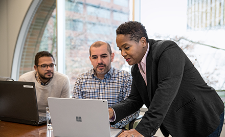 Image of a team of three collaborating over a computer.