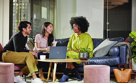 Image of three colleagues chatting on a couch at work.