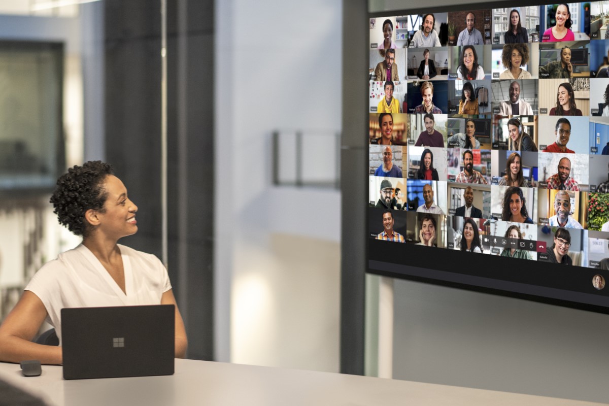 Adult female meeting in a conference room while using Microsoft Teams Together Mode on a Surface Hub 2S 85&rdquo; device.