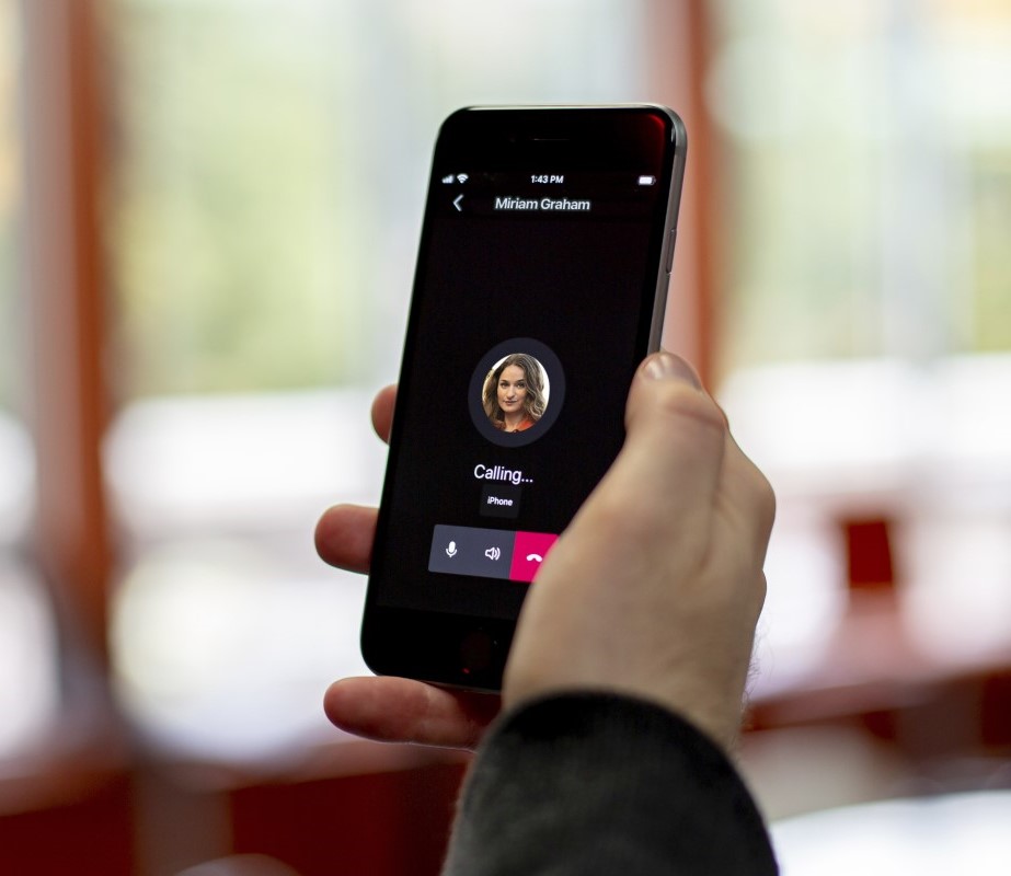 A close-up of a hand holding an iPhone showing a calling screen on Microsoft Teams.