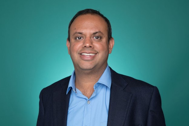 Headshot of Manik Gupta set against teal backdrop.