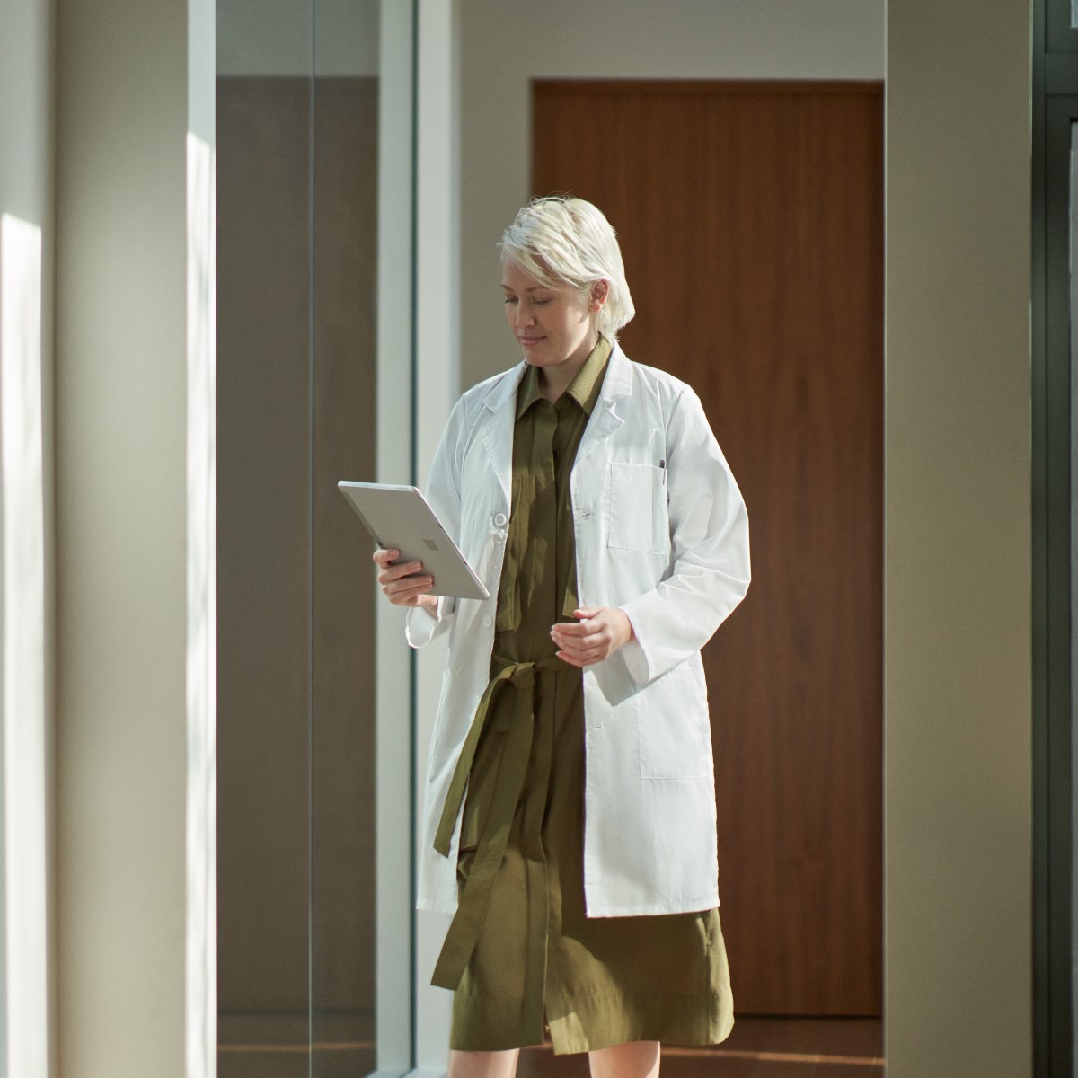 Doctor walking to office to take a telehealth video call via a tablet.
