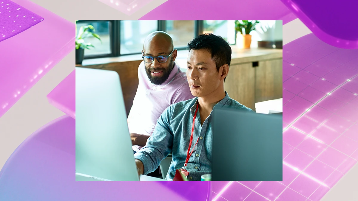 Two people sitting at a desk in an office looking at a computer. Behind the image is a colorful purple graphic design background.