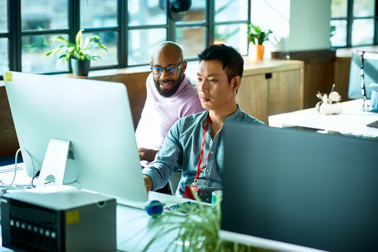 A group of men looking at a computer screen in an office.