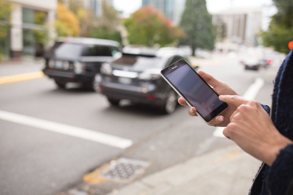A person holding a cellphone standing on the sidewalk
