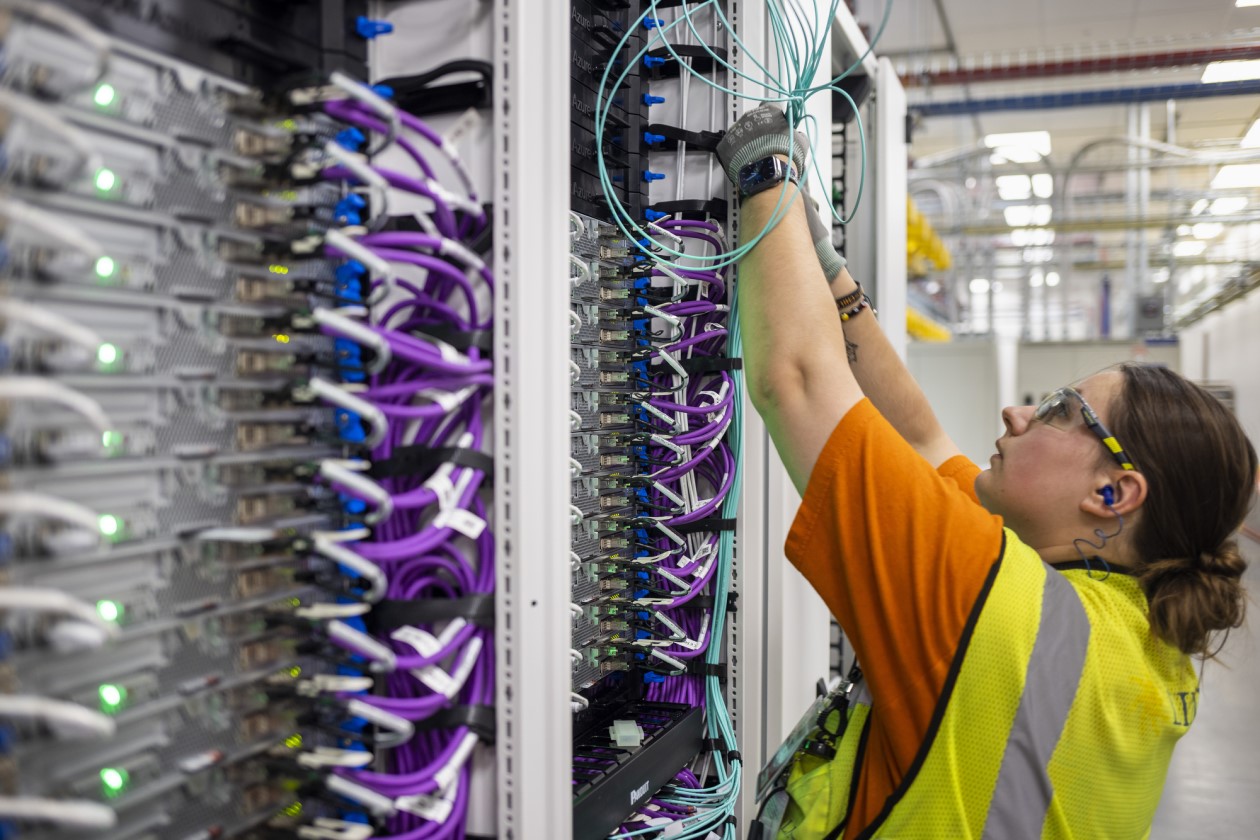 A datacenter employee dressed in a yellow vest working on technology