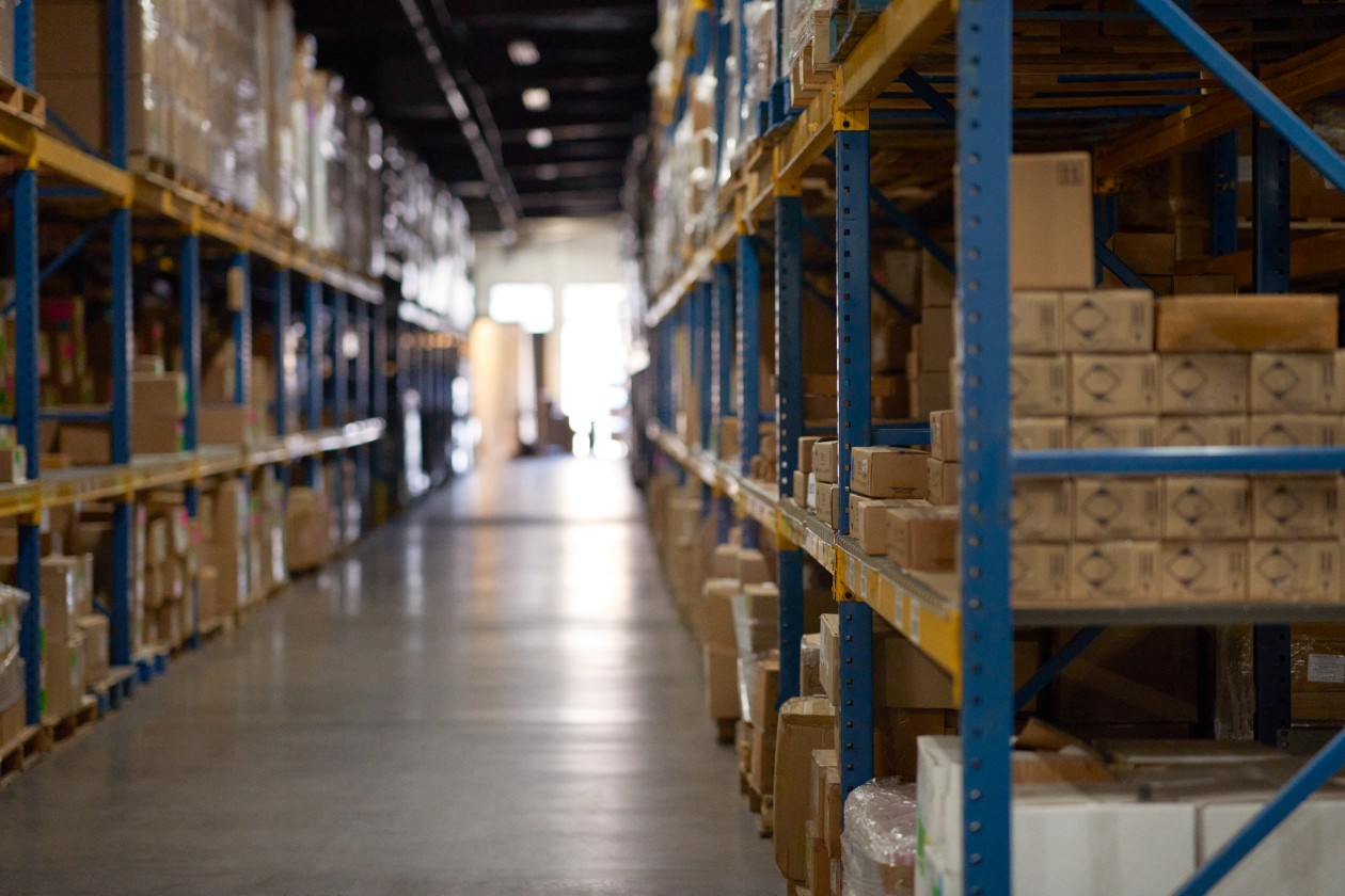 Cinematic wide shot of warehouse with silhouette of worker in background.