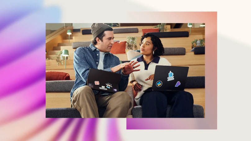 A man and woman sitting on stairs with laptops