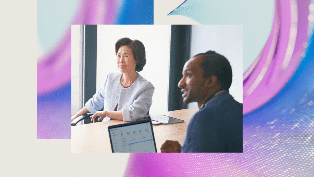 Two people sitting in a conference room looking at a computer screen.