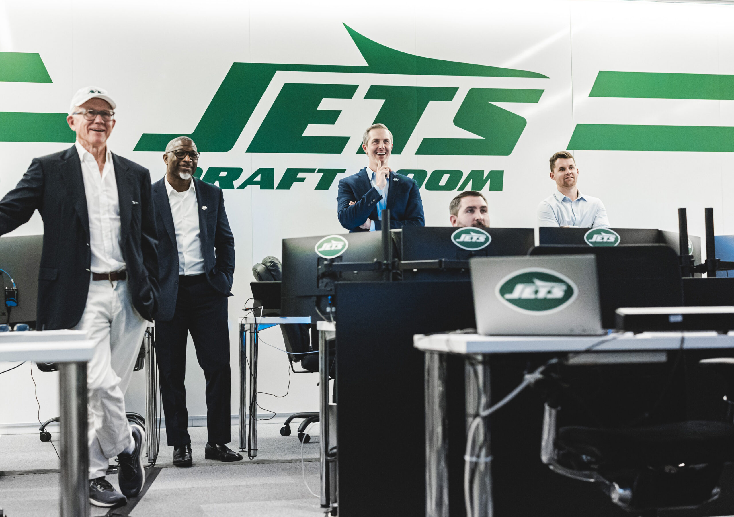 New York Jets staff smiling in their draft room.