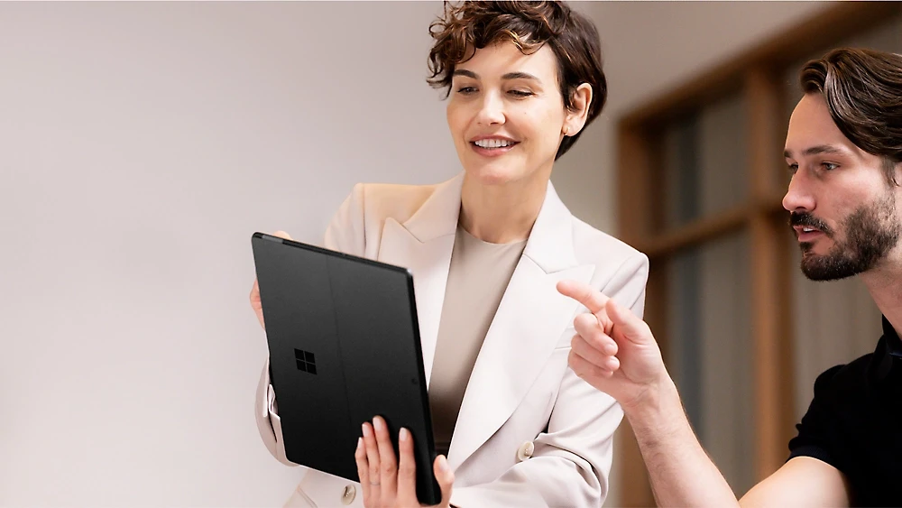 A woman holding a tablet and pointing at something