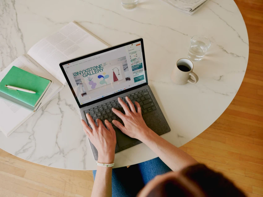 Decorative, over the shoulder view of a person typing on a Surface Laptop 5.