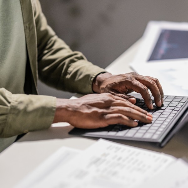 Close-up of hands typing on the keyboard of a Surface tablet.