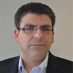 a man wearing a suit and tie smiling and looking at the camera