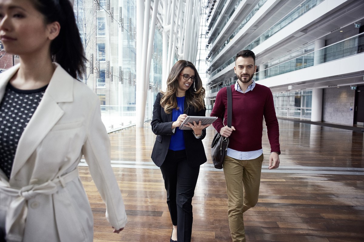 Female and male business professionals walking in foyer working on a Surface Pro.