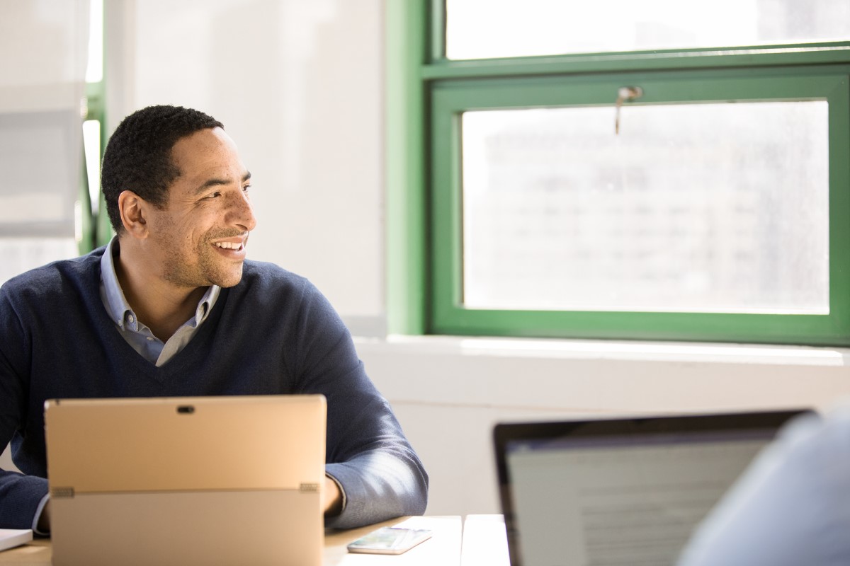 Man sits at a desk with a computer and looks out the window.