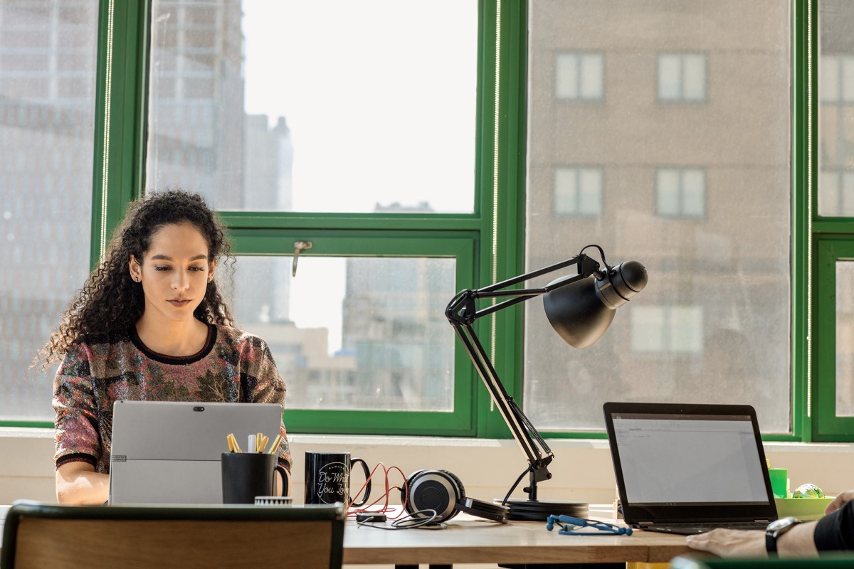 Young, small business female with laptop in modern workplace.