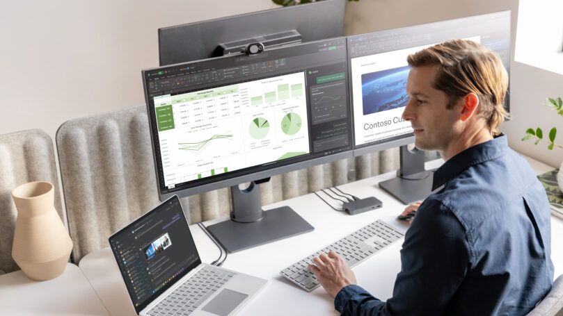 A man sitting at a desk with multiple computer screens