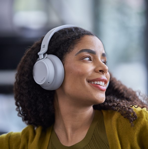 a person wearing headphones, looking to the side, smiling