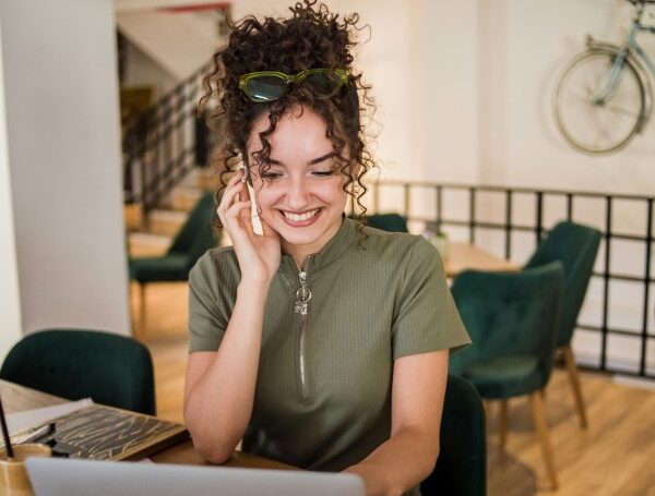 A woman sitting at a table with a laptop and phone