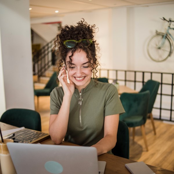 A woman sitting at a table with a laptop and phone