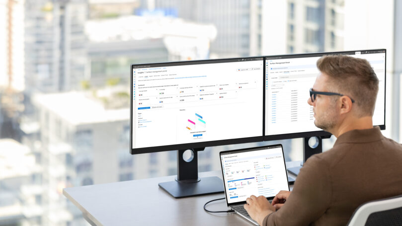 A man sitting at a desk with two computers