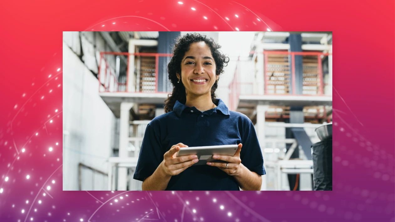 A woman stands in a warehouse holding a tablet.