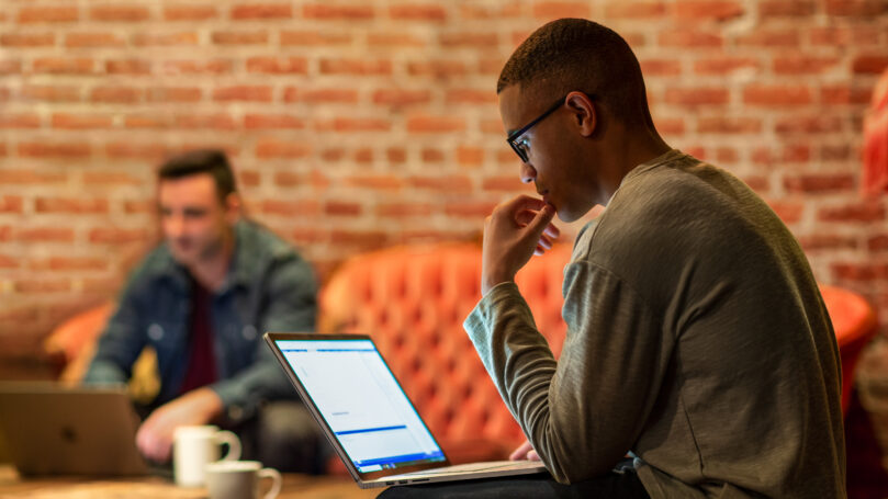 A man sitting on a couch using a laptop