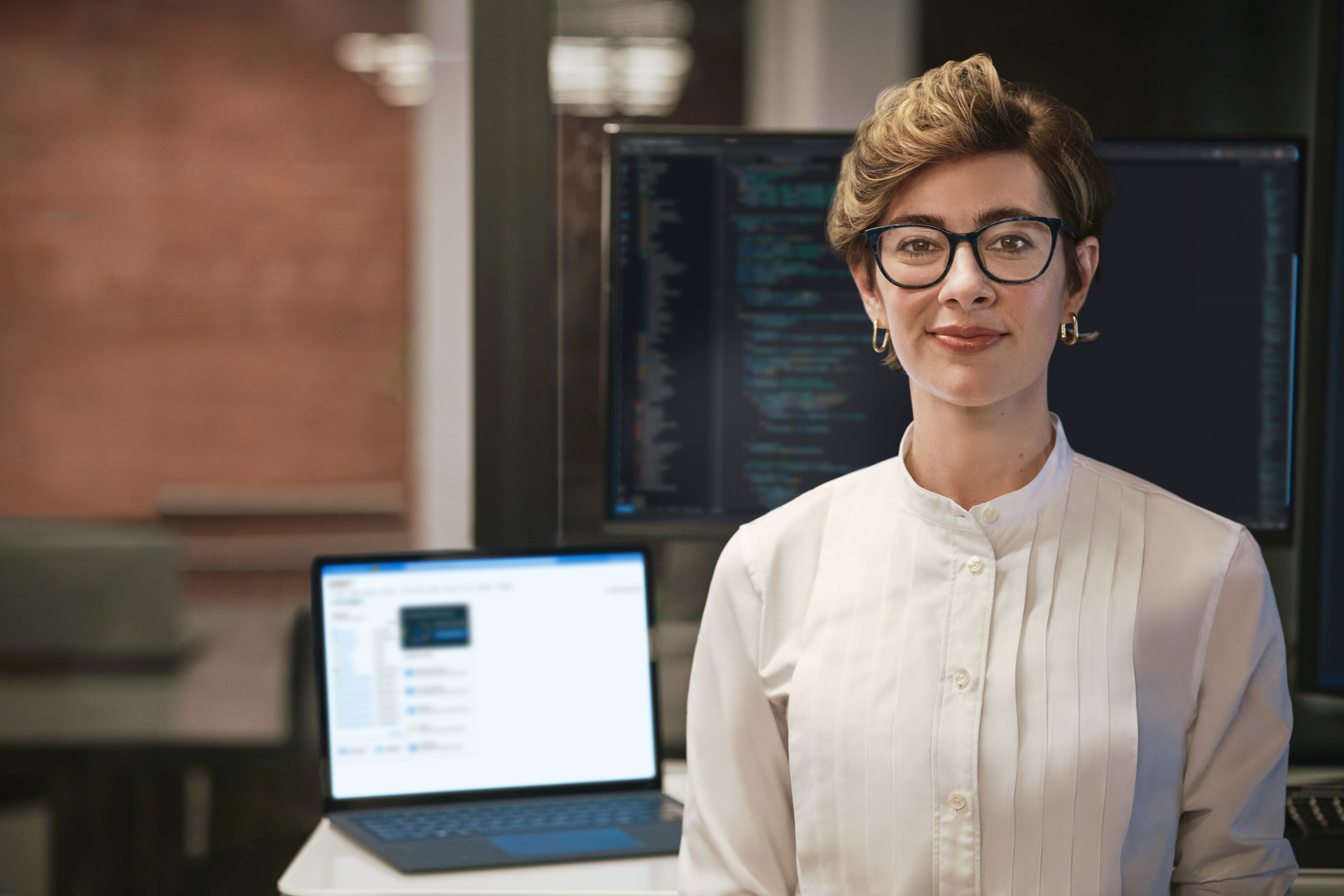 A woman in glasses sitting in front of a laptop
