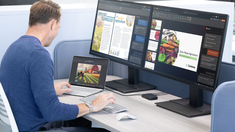 A man sitting at a desk with a laptop and a computer