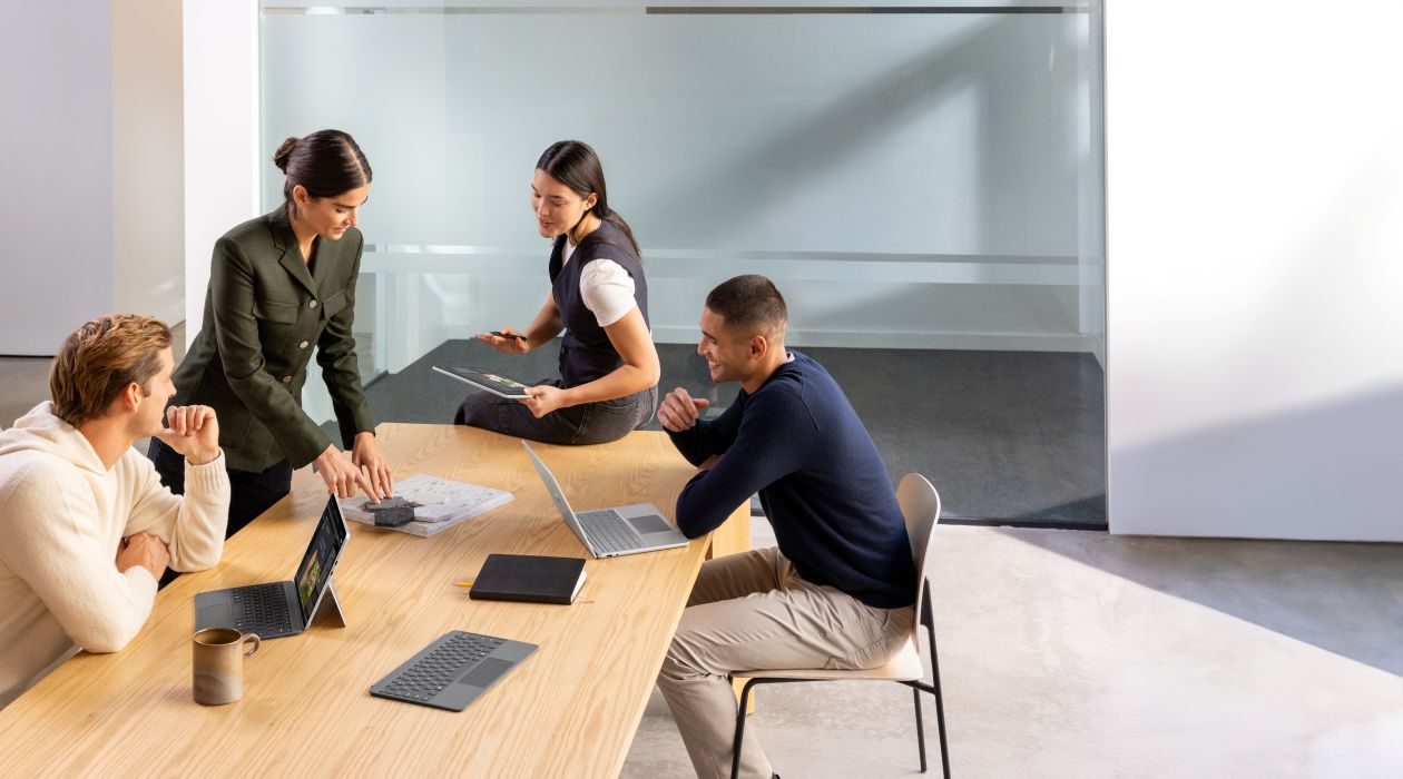 A group of people sitting around a table with laptops