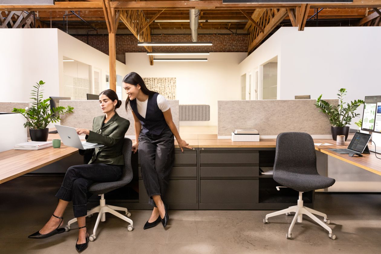 Two coworkers working in cubicle looking at computer monitor.