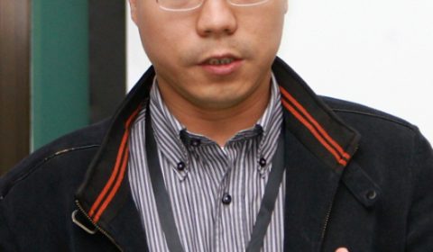 a man wearing glasses and smiling at the camera