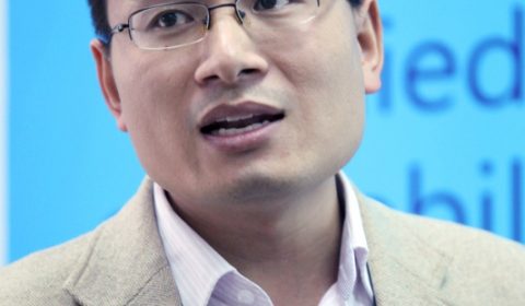 a man wearing a suit and tie smiling and looking at the camera