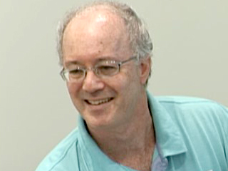a man wearing glasses and smiling at the camera