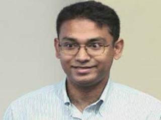 a man wearing glasses and smiling at the camera