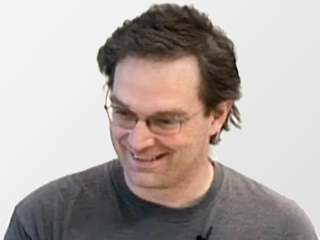 a man wearing glasses and smiling at the camera