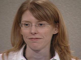 a woman wearing glasses and smiling at the camera